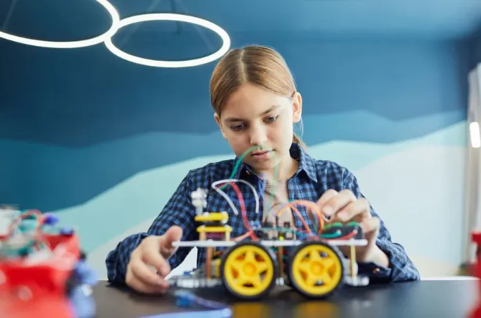 A girl wiring up a robotic car she is building